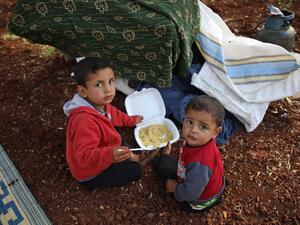 Displaced Syrian children eat in a field near a camp for displaced people in the village of Atme, in the jihadist-held northern Idlib province on May 8, 2019. (AFP)