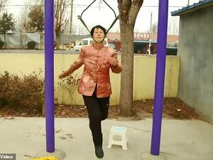 Pensioner Song Lianyun, 68, carefully placing her head between two straps, one of them under her jaw and one of them at the nape of her neck. (Pear Video Screenshot)