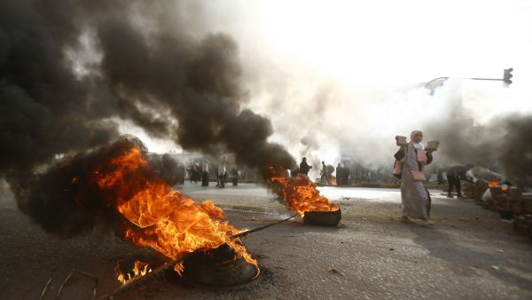 A Sudanese protester walks past burning tyres as military forces tried to disperse the sit-in outside Khartoum's army headquarters on June 3, 2019. (AFP/ File)