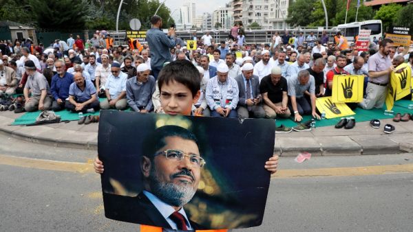 A boy holds a picture of the Egyptian President Mohamed Morsi during a symbolic funeral prayer on June 18,2019 in front of the embassy in Ankara. (AFP/ File Photo)