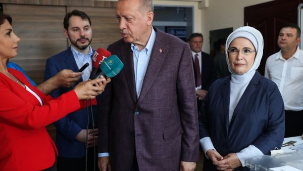 Turkish President Recep Tayyip Erdogan (C), flanked by his wife Emine (R), speaks to journalists after casting his ballot at a polling station, in Istanbul, on June 23, 2019, during local elections. (AFP/ File Photo)