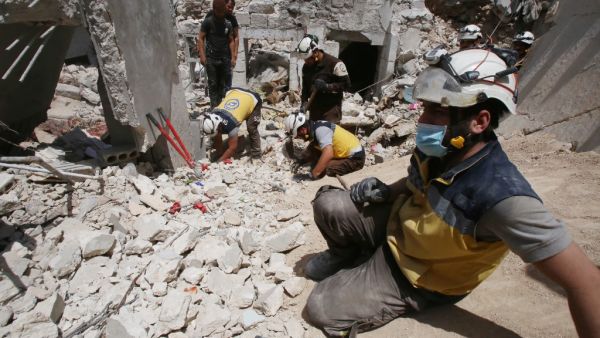 Members of the Syrian Civil Defence (White Helmets) clear debris as they search for bodies or survivors in a collapsed building following a reported regime air strike on the town of Ariha, in the south of Syria's Idlib province, on July 12, 2019. (AFP)
