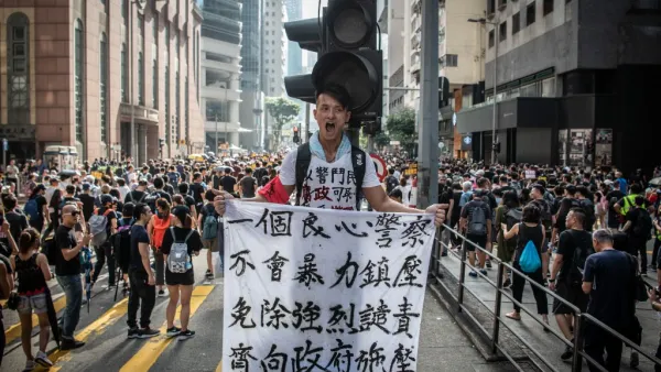 A protester in Wan Chai holds a sign denouncing police violence during a march against a controversial extradition bill in Hong Kong on July 21, 2019. Another huge anti-government march kicked off in Hong Kong on July 21 afternoon with seemingly no end in sight to the turmoil engulfing the finance hub, sparked by years of rising anger over Beijing's rule.  Laurel CHOR / AFP