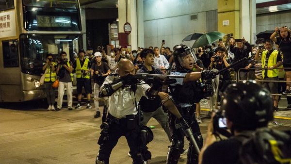 A police officer (C) points a firearm during clashes with protesters who had gathered outside Kwai Chung police station, in support of protesters detained with the charge of rioting, in Hong Kong on July 30, 2019. (ISAAC LAWRENCE / AFP)
