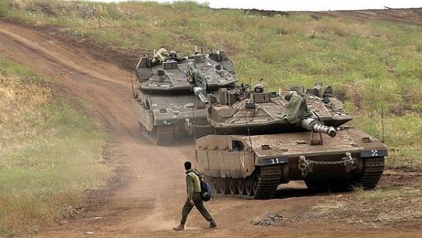 An Israeli soldier next to Merkava Mark IV tanks in the Golan Heights during a military drill on May 7, 2018. (AFP Photo/Jalaa Marey)