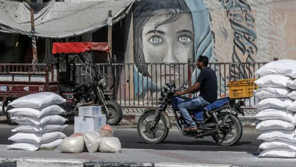 A Palestinian man rides his motorcycle outside an aid distribution centre run by the United Nations Relief and Works Agency (UNRWA) in the central Gaza Strip refugee camp of Bureij (AFP)