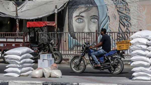 A Palestinian man rides his motorcycle outside an aid distribution centre run by the United Nations Relief and Works Agency (UNRWA) in the central Gaza Strip refugee camp of Bureij (AFP)