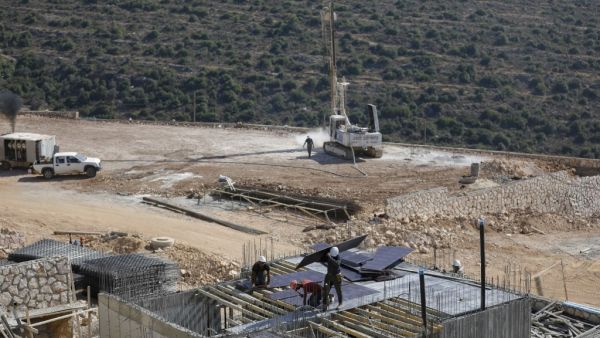 Palestinian labourers work at a construction site in the Israeli settlement  (AFP)