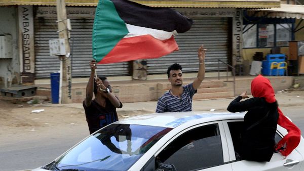 Sudanese demonstraters wave their national flag (AFP)