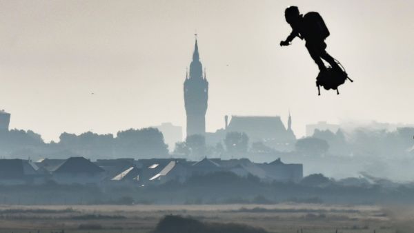 Franky Zapata on his jet-powered "flyboard" flies past the belfry of the city hall of Calais (C) after he took off from Sangatte, northern France (AFP)