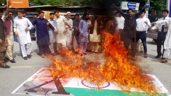 Kashmiris chant slogans beside a burning Indian flag with a photograph of Indian Prime Minister Narendra Modi during a protest in Muzaffarabad, the capital of Pakistan controlled Kashmir (AFP)