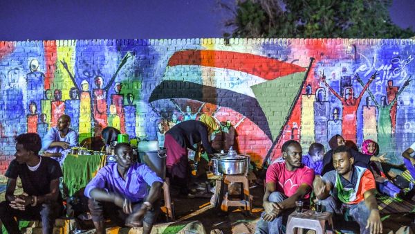 Sudanese protesters sit in front of a recently painted mural during a demonstration near the army headquarters in the capital Khartoum. (AFP)