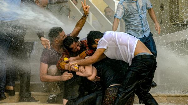 Demonstrators protect each other as they are hit by water cannon during a protest against the replacement of Kurdish mayors with state officials in three cities, in Diyarbakir, in eastern Turkey (AFP)