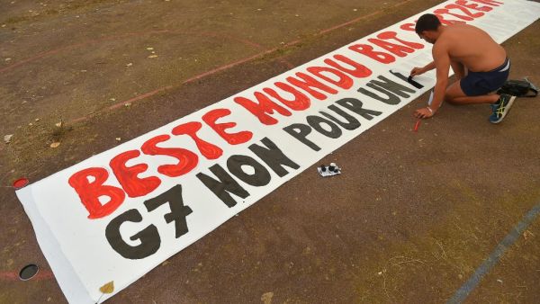 A man paints a banner reading in Basque and French "G7, no for another world" at a campsite in Urrugne on August 22, 2019 ahead of a Group of Seven (G7) summit to be held in nearby Biarritz. (AFP)