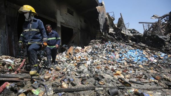 Iraqi firefighters inspect the charred remains of a warehouse in Baghdad's Sadr City on August 23, 2019, after a large fire broke out overnight. (AHMAD AL-RUBAYE / AFP)