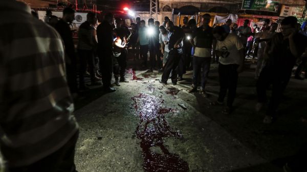 Palestinians look at blood stains on the ground after an unknown explosion near a police checkpoint in Gaza City on August 27, (AFP/ File Photo)
