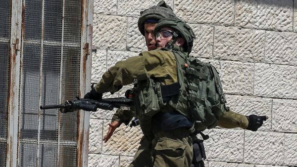 An Israeli soldier throws a stun grenade during clashes (AFP)