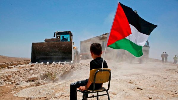 A Palestinian boy sits on a chair with a national flag as Israeli authorities demolish a school site in the village of Yatta, south of the West Bank city of Hebron and to be relocated in another area, on July 11 2018. (Hazem Bader/AFP / Getty Images)