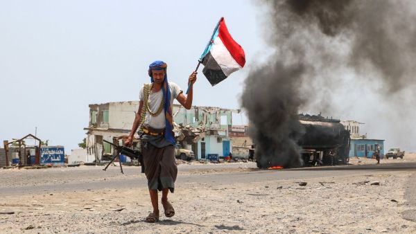 A fighter of the UAE-trained Security Belt Force, dominated by members of the Southern Transitional Council (STC) which seeks independence for south Yemen, walks with a separatist flag past an oil tanker set ablaze in Aden. (AFP/ File Photo)