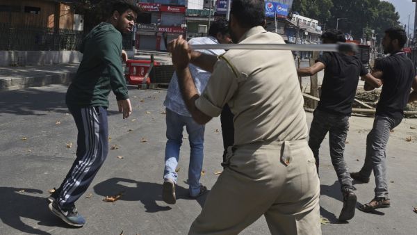 An Indian policeman clashes with Indian Kashmiri Shiite during a strict curfew in Lal Chowk area of Srinagar (AFP)