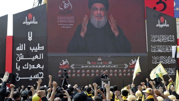 Supporters of the Lebanese Shiite Hezbollah movement react to a speech by their leader Hassan Nasrallah, transmitted or a large screen during a religious mourning procession on the tenth day of the lunar month of Muharram, which marks the day of Ashura, in a suburb of the capital Beirut, on September 10, 2019. (AFP/ File Photo)