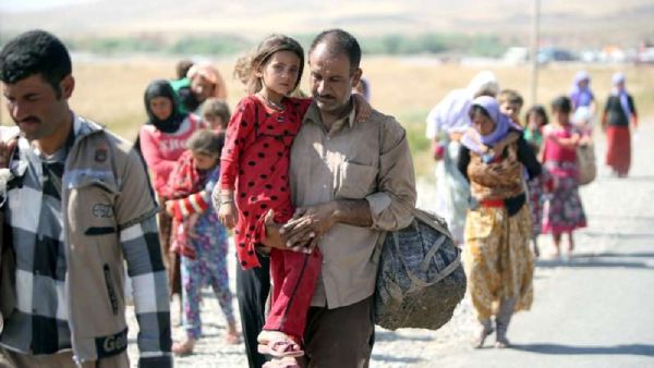 A displaced Iraqi man from the Ezidi community carries his daughter as they cross the Iraqi-Syrian border. (AFP /AHMAD AL-RUBAYE)