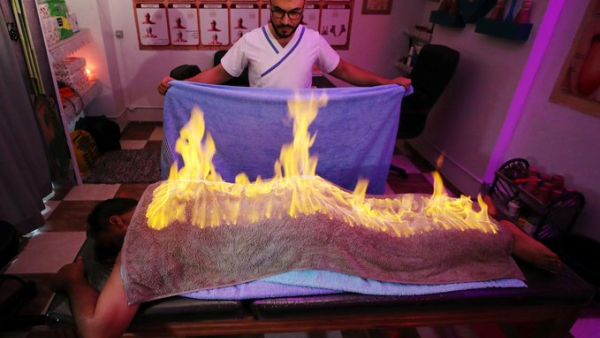 Massage therapist Abdel Rehim Saeid performs the fiery towel method to ease a patient's muscle pain in Gharbia, Egypt. (Twitter)