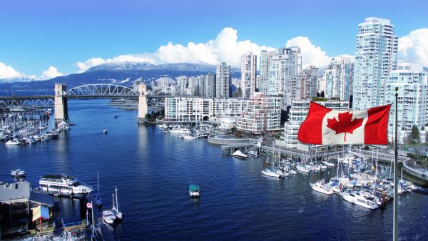 Canadian flag in front of view of False Creek and the Burrard street bridge in Vancouver, Canada (Shutterstock)	