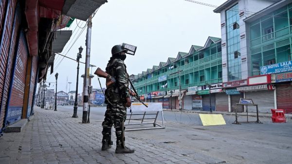 A security personnel stands guard to block a road near closed shops while strict restrictions are imposed during a lockdown in Srinagar on September 28, 2019. (Tauseef MUSTAFA / AFP)