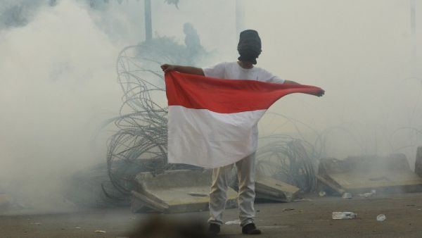 A protester carries the national flag through teargas smoke during a demonstration in Jakarta on September 30, 2019. (AFP/ File Photo)