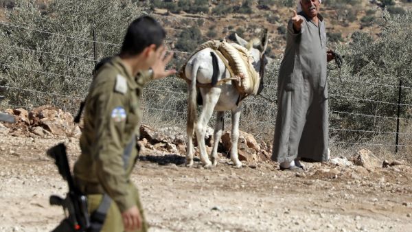 A Palestinian farmer reacts as an Israeli soldier walks past him during a demonstration against the closure of agricultural roads leading to the olive fields in the village of Kafr Thulth, east of Qalqilya in the occupied West Bank, on October 4, 2019. (Jaafar ASHTIYEH / AFP)