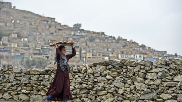 A young girl carries bread on a tray over her head at a hillside overlooking Kabul on October 6, 2019. (WAKIL KOHSAR / AFP)