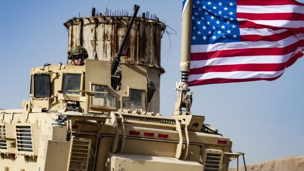 A US soldier sits atop an armoured vehicle during a demonstration by Syrian Kurds against Turkish threats next to a base for the US-led international coalition on the outskirts of Ras al-Ain town in Syria's Hasakeh province near the Turkish border  (AFP)