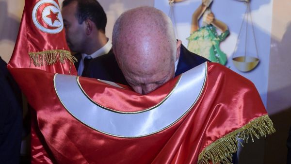 Conservative academic Kais Saied kisses the Tunisian flag as he celebrates his victory in the Tunisian presidential election in the capital Tunis  (AFP)
