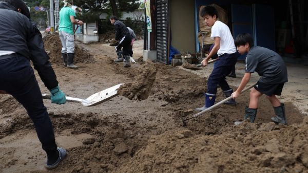 Residents clear mud from a street at the flooded area in Marumori, Miyagi prefecture on October 14, 2019, in the aftermath of Typhoon Hagibis. Tens of thousands of rescue workers were searching for survivors of powerful Typhoon Hagibis, two days after the storm slammed into Japan, killing at least 35 people. (Jiji Press / AFP)
