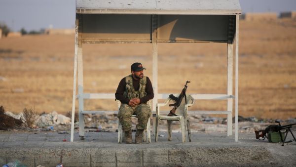 A turkish-backed Syrian fighter sits on the side of the street in the town of Ayn al-Arus, south of the border town of Tal Abyad (AFP)