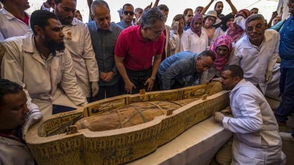 Egypt's Antiquities Minister Khaled el-Enany (4-R), and Mostafa Waziri (3-R), the Secretary General of the Supreme Council of Antiquities, surround a sarcophagus belonging to a man in front the Hatshepsut Temple at the Valley of the Kings in Luxor on October 19, 2019. Khaled DESOUKI / AFP