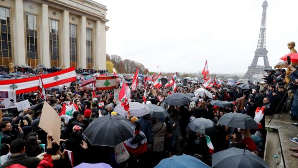 People hold signs and wave Lebanon national flags as they take part in a demonstration to support Lebanese protests, on October 20, 2019 in front of the Eiffel Tower at the Trocadero in Paris. (FRANCOIS GUILLOT / AFP)