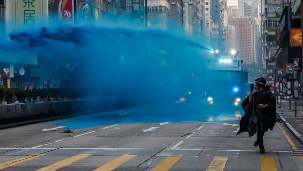 A protester runs from advancing police as they deploy a water cannon on a road in the Tsim Sha Tsui district in Hong Kong on October 20, 2019. Police fired water cannon and tear gas at Hong Kongers who defied authorities with an illegal march on October 20, their numbers swollen by anger over the recent stabbing and beating of two pro-democracy protesters.  DALE DE LA REY / AFP