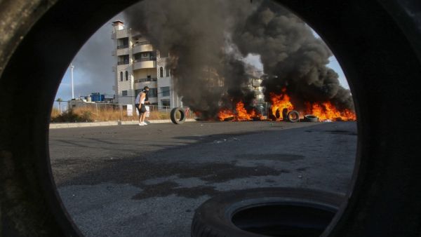 Lebanese protesters block a road with burning tires during ongoing anti-government demonstrations in the southern coastal city of Saida (Sidon) on October 28, 2019. Lebanese demonstrators set up barricades and parked cars across key roads today to protest corruption and press their demands for a radical overhaul of their country's sectarian political system. Defying pleas from Lebanon's top leaders, protesters sought to keep the country on lockdown by cutting off some of the main thoroughfares, including th