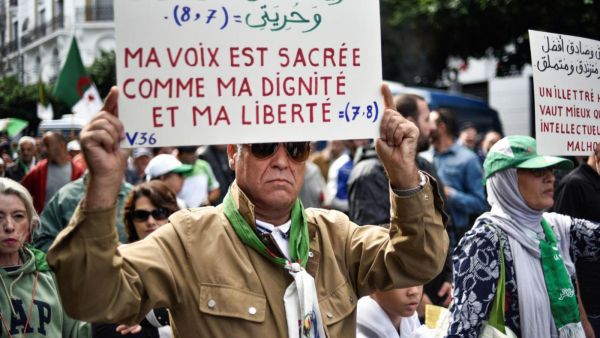 Protester in Algiers holds up sign that reads: 'My voice is sacred just like my dignity and my freedom' (AFP)