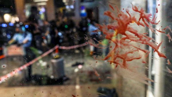 Blood is seen splattered on a glass panel at the entrance of a shopping mall as riot police secure the scene after a bloody knife fight broke out in Hong Kong on November 3, 2019. A bloody knife fight in Hong Kong left six people wounded on November 3 evening, including a local pro-democracy politician who had his ear bitten off, capping another chaotic day of political unrest in the city. VIVEK PRAKASH / AFP
