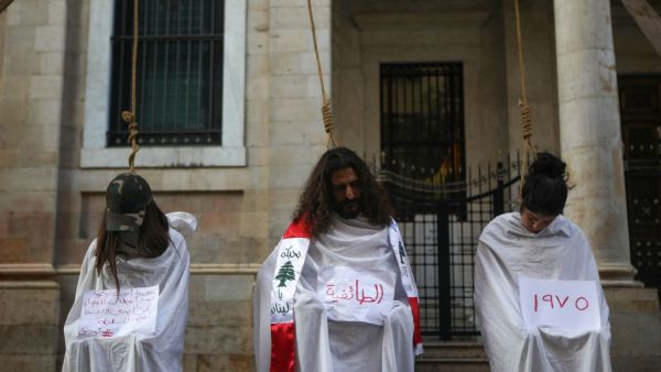 Lebanese protesters stage a mock hanging in a symbolic performance against sectarianism (C), Lebanon's 1975-90 civil war (R) and corruption during ongoing anti-government demonstrations in Downtown Beirut on November 3, 2019. (Patrick BAZ / AFP)
