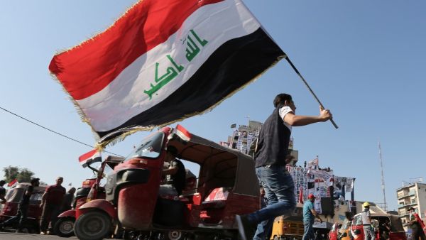An Iraqi protester waves the natioanl flag in Tahrir square in the capital Baghdad on November 5, 2019, amid ongoing anti government demonstrations. Iraqi security forces fired live rounds yesterday at protesters in Baghdad, after four demonstrators were shot dead overnight outside the Iranian consulate in the holy city of Karbala. (SABAH ARAR / AFP)