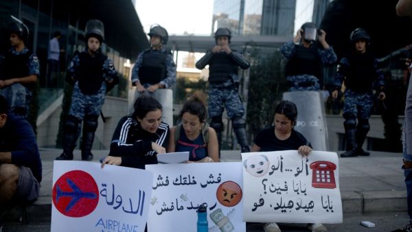 Lebanese anti-government protesters sit in front of riot police at the headquarters of MTC-Touch, a telecom company, in Beirut on November 5, 2019.  (AFP/ File Photo)