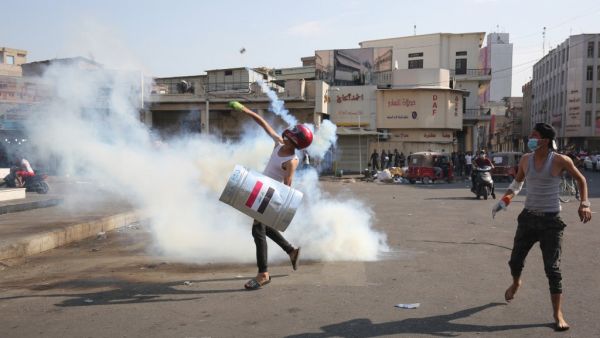 Iraqi demonstrators run amidst tear gas on the Martyrs' Bridge (Jisr Al-Shuhada) during ongoing anti-government demonstrations, in the capital Baghdad on November 7, 2019.  AHMAD AL-RUBAYE / AFP
