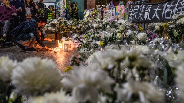 Mourners pay their respects next to flowers and a banner which reads "From all of us - God bless Chow Tsz-Lok" at the site where student Alex Chow, 22, fell during a recent protest in the Tseung Kwan O area on the Kowloon side of Hong Kong on November 8, 2019. (AFP)