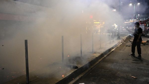 A bystander records footage with his mobile phone as firemen extinguish a burning barricade after a protest in the Tuen Mun district of Hong Kong on November 10, 2019. The international finance hub has been upended by five months of huge and increasingly violent rallies, but Beijing has refused to give in to most of the movement's demands. Philip FONG / AFP