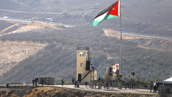 A picture taken from the Israeli side of the border shows King Abdullah II of Jordan (L) standing to attention with army troops under a Jordanian national flag during a ceremony at the Jordan Valley site of Naharayim, also known as Baqura, east of the Jordan River on November 11, 2019. (AFP/ File Photo)