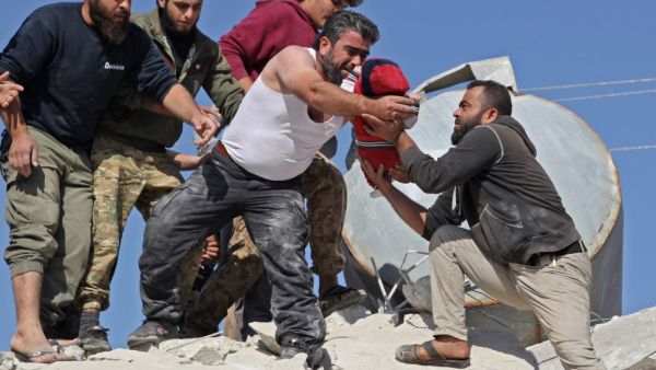 A Syrian man carries a wounded baby pulled from the rubble of a building after a reported airstrike by pro-government forces on the village of Shinan in the northwestern Idlib province, on November 12, 2019. Abdulaziz KETAZ / AFP